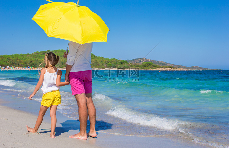父亲和女儿在白色沙滩上带着黄色