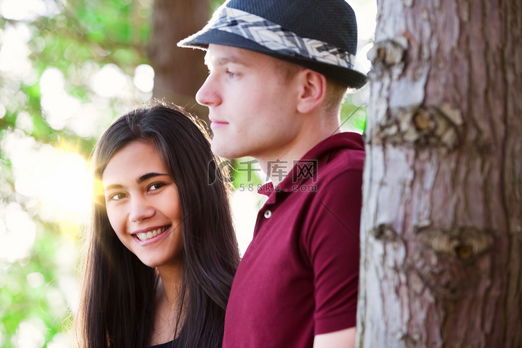 年轻夫妇站在树丛中，阳光洒落