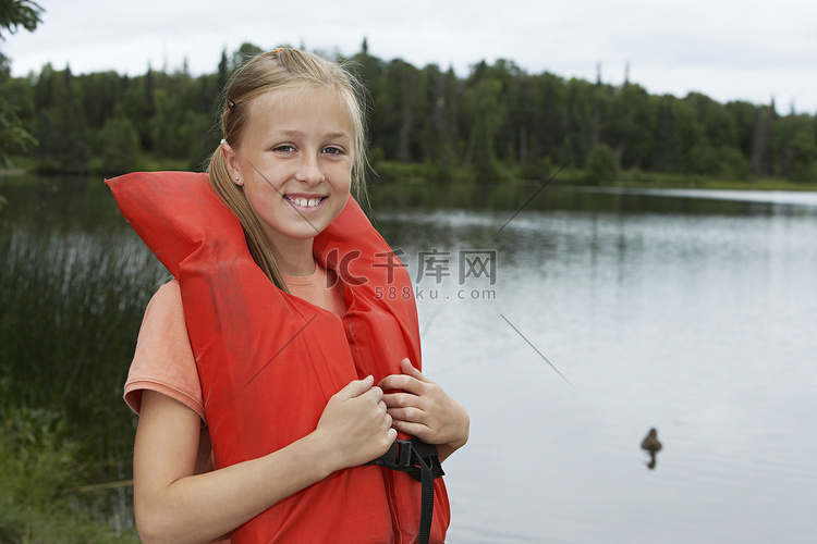 站在湖边穿着救生衣的年轻女孩的