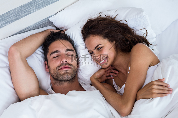 微笑的女人看着躺在床上放松的男