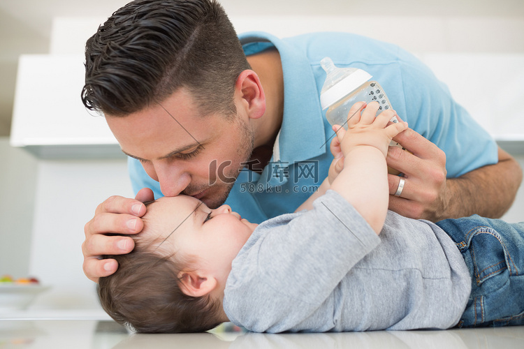 慈爱的父亲在额头上亲吻婴儿