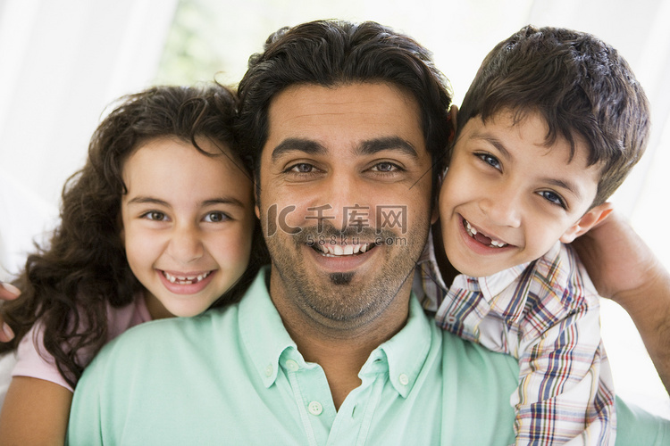 父亲和两个年幼的孩子在客厅微笑