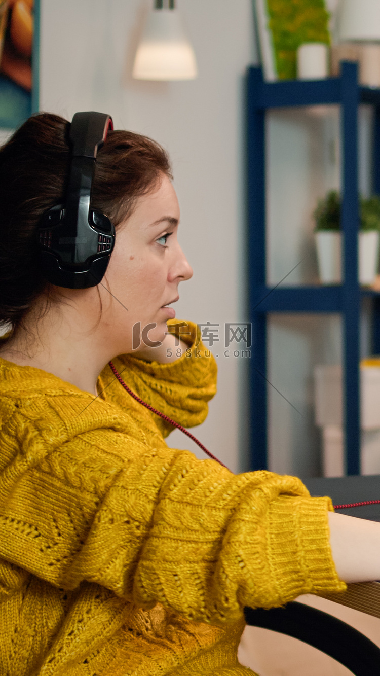 专注的女玩家坐在桌上，戴上耳机