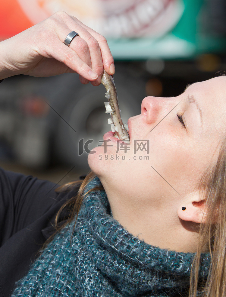 荷兰妇女吃着典型的生鲱鱼