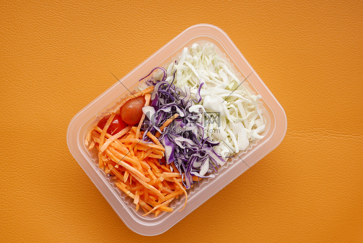 橙色背景中塑料容器中的新鲜蔬菜