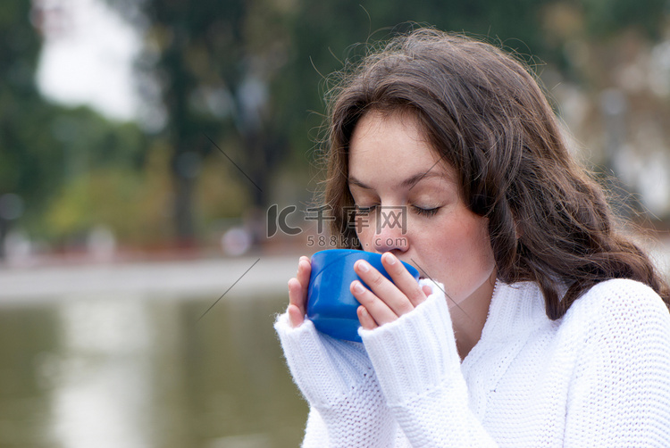 在户外喝热茶的年轻女子的画像