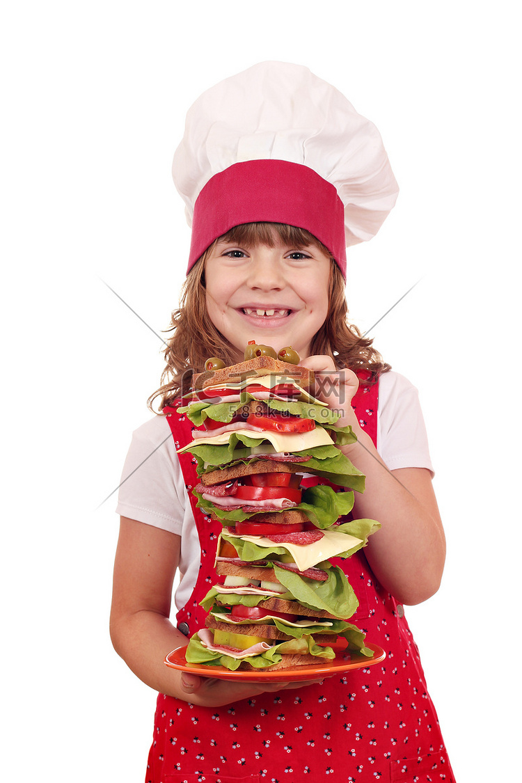 快乐的小女孩厨师拿着高三明治的