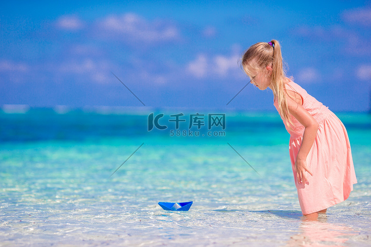 可爱的小女孩在绿松石海中玩折纸