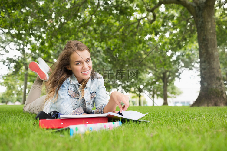 躺在草地上学习的快乐年轻学生