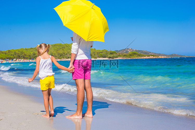 白色海滩的小女孩和年轻爸爸有黄