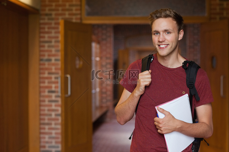 站立在走廊的英俊的微笑的学生