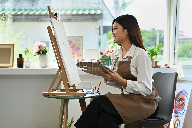 女画家坐在画布前用水彩画画的侧