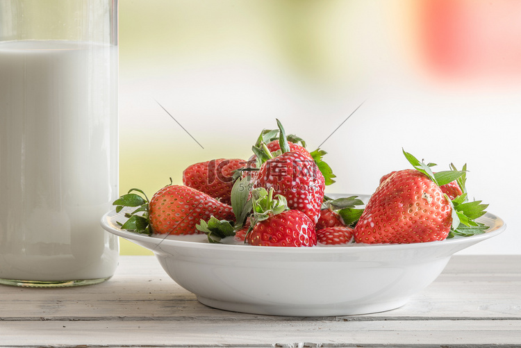 盘子里的草莓和一瓶牛奶