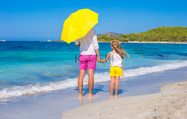 白色海滩的小女孩和年轻爸爸有黄