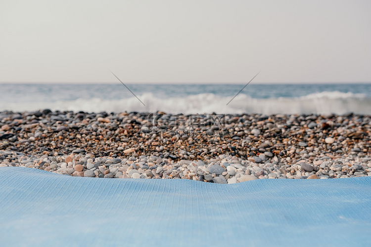 蓝色瑜伽垫位于海边的卵石沙滩上