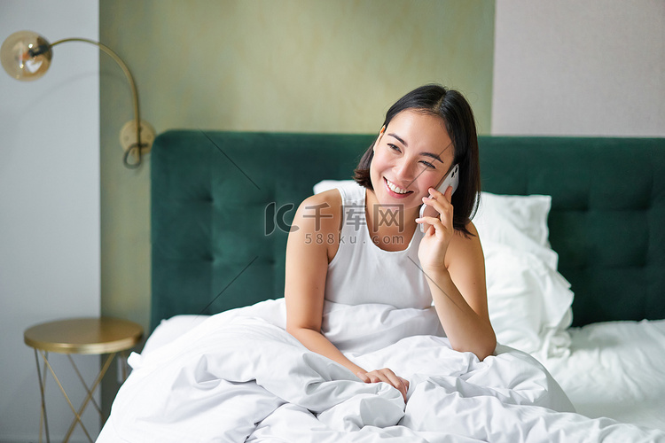 美丽的韩国年轻女性打电话，在床