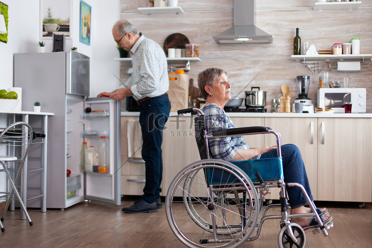 坐在轮椅上的残疾老年妇女坐在厨