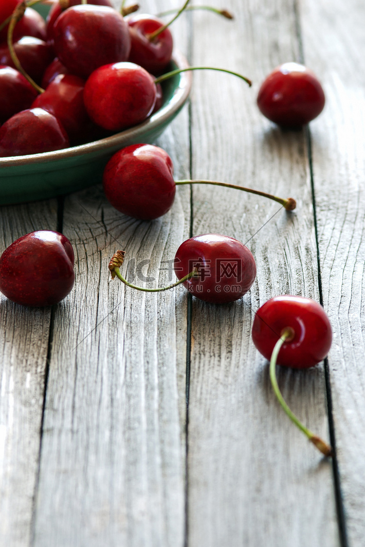 木桌陶瓷盘中的红樱桃，垂直拍摄