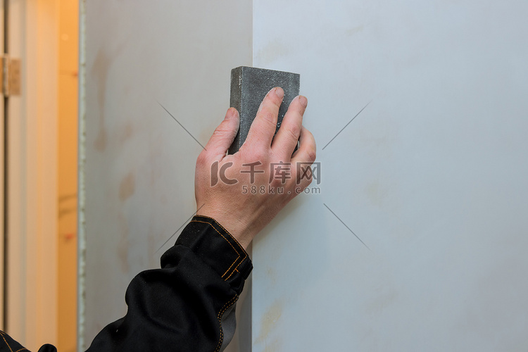 工人在装修房屋时用砂刀打磨干墙