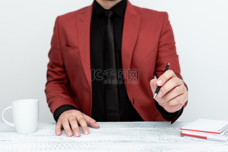 穿着红色西装的男模特坐在白桌旁