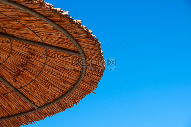 遮阳伞稻草屋顶映衬着蓝天。