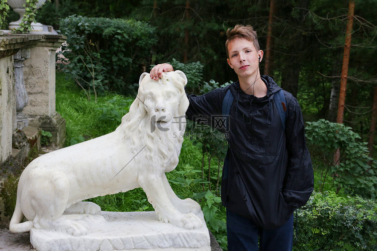 一个可爱的男孩站在一尊狮子石像