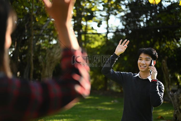 友好的亚洲男人拿着手机在公园里