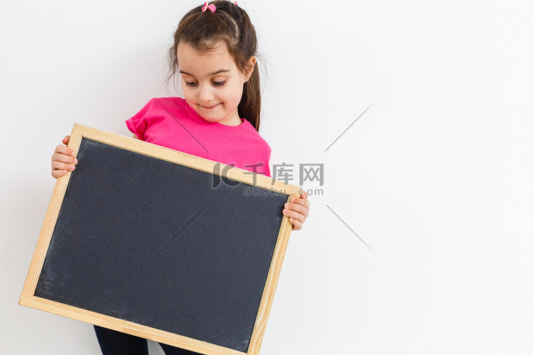 微笑的小女生拿着空白粉笔板与复