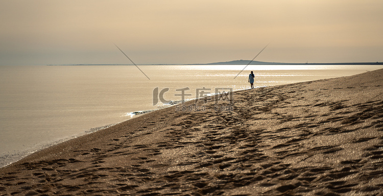 一位穿着沙滩裙的苗条女人在日落