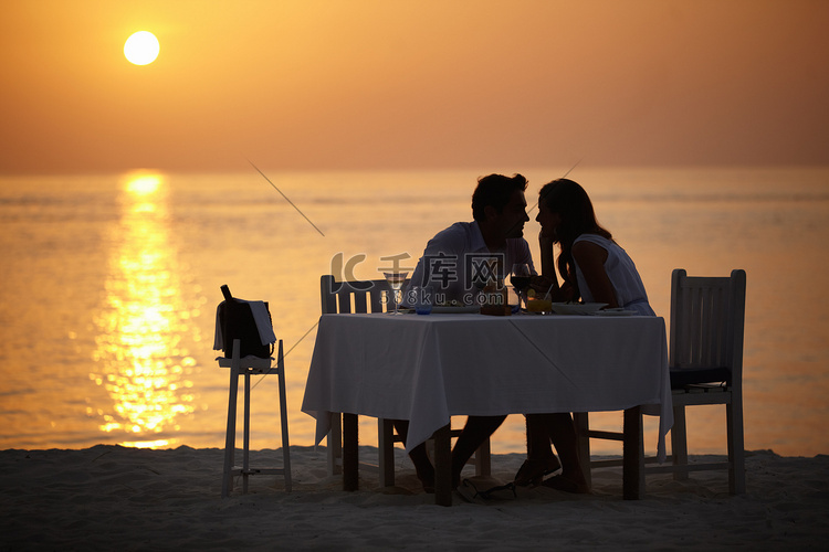 爱情、海洋日落和情侣在餐桌上度