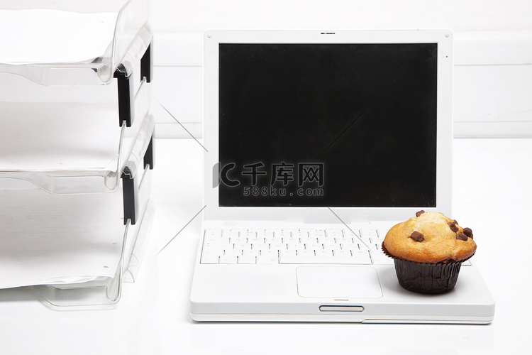 办公纸架旁的纸杯蛋糕和笔记本电