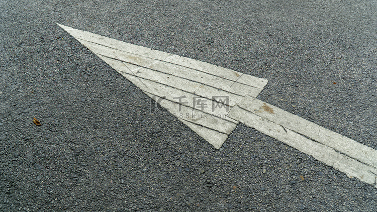 灰色铺砌道路上的白色箭头标志指