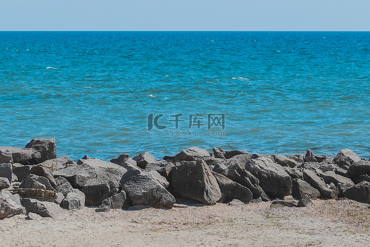 在海岸的防波堤海滩石头有蓝色的