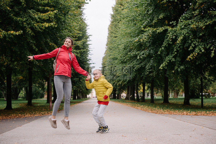 母亲和儿子在秋天的公园里跳跃。