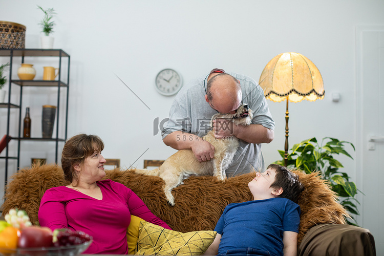 父亲抱着毛茸茸的狗，亲吻它的头