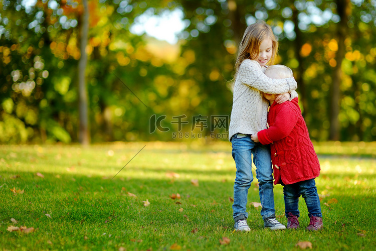 两姐妹在美丽的秋季公园玩得开心