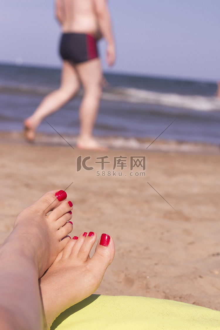 海沙上指甲涂成红色的女人的脚