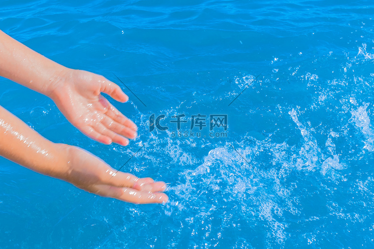 一个小女孩的手溅起蓝色纯净的海