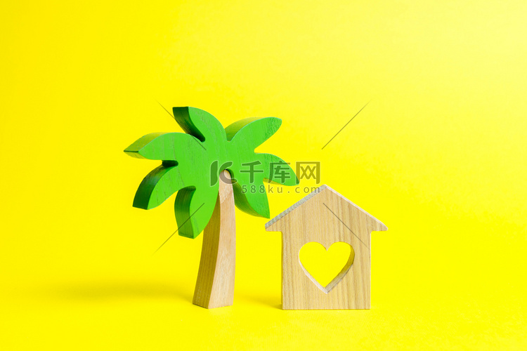木棕榈树和黄色背景上有心的房子