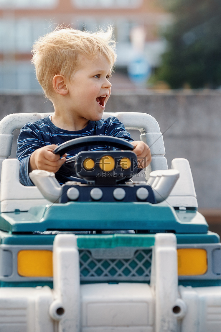 小男孩驾驶带方向盘的大玩具车在