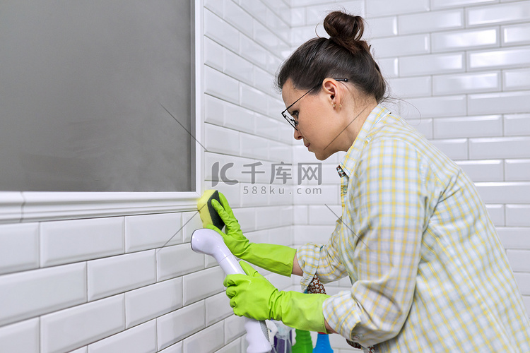 女人做浴室清洁，用蒸汽洗瓷砖墙
