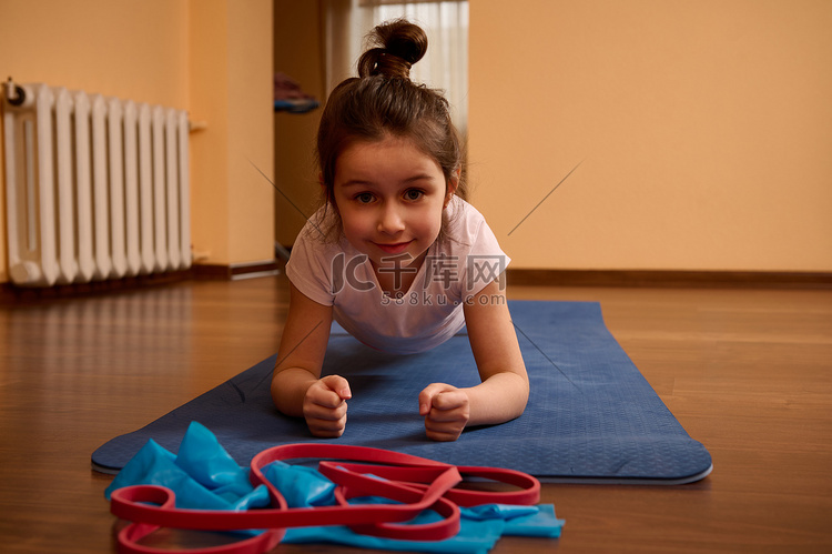 坚定的运动小女孩在蓝色健身垫上