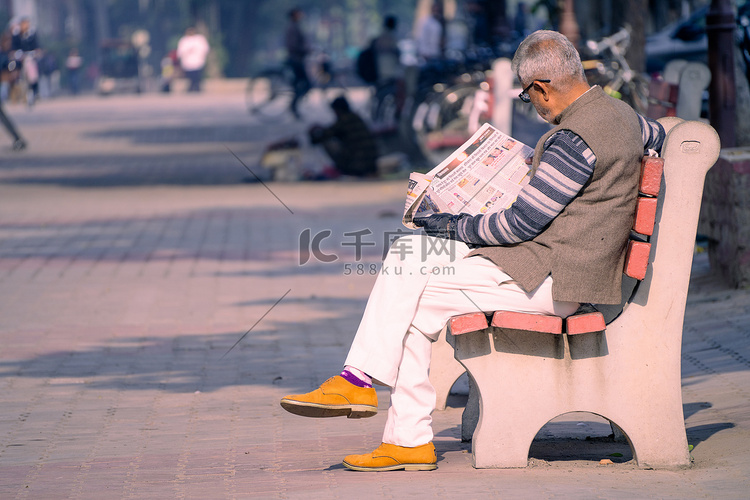 老人坐在阳光明媚的公园长椅上，