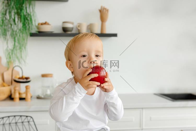 孩子坐在厨房里吃一个苹果作为早