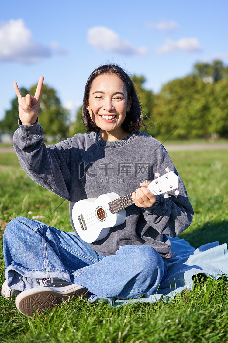 快乐的亚洲女孩在公园里弹尤克里