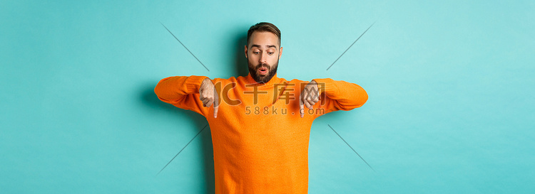 穿着橙色毛衣的惊奇男人，手指向