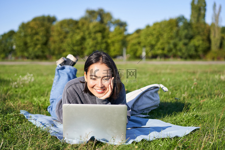 微笑的亚洲女孩躺在公园的草地上