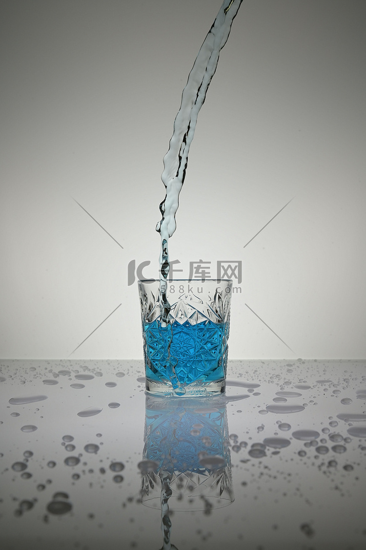 蓝色液体垂直射入水晶玻璃，周围