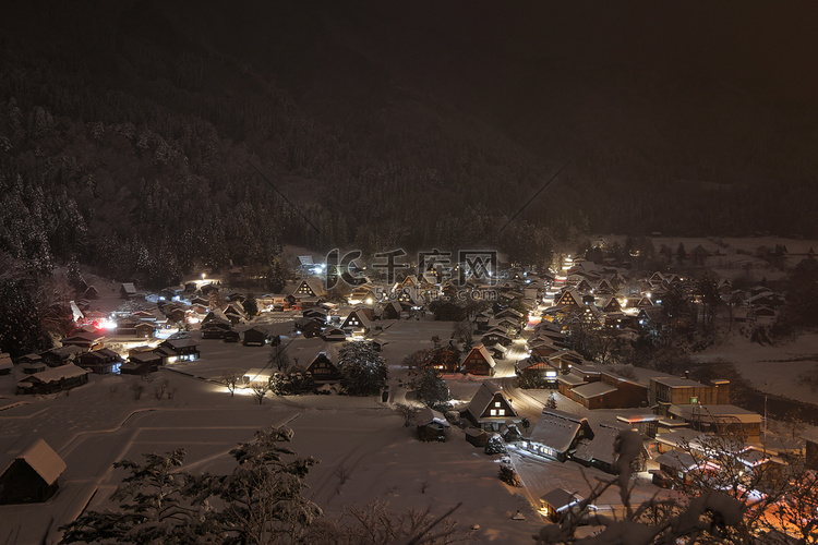 夜晚传统山村的灯光刺破雪雾