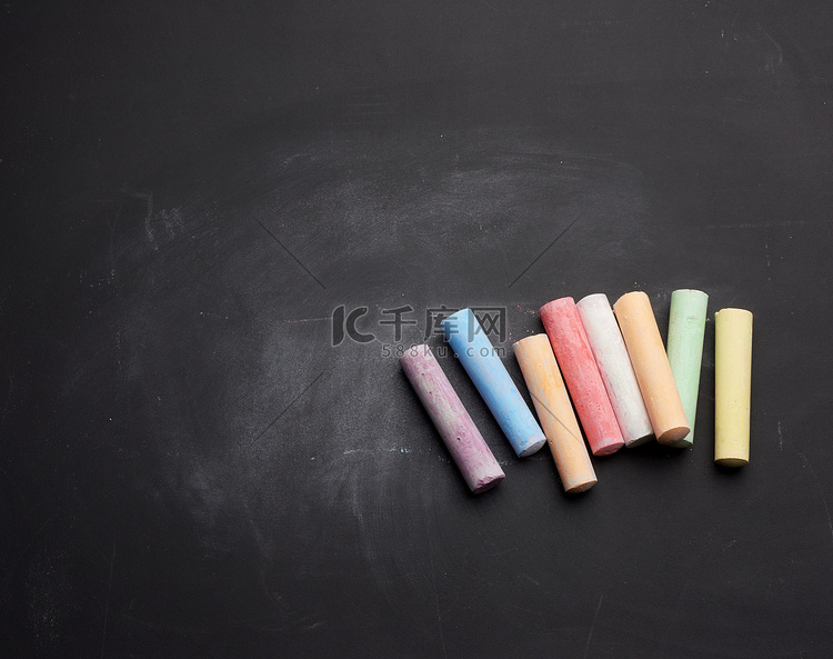 多彩多姿的粉笔躺在空的黑色粉笔